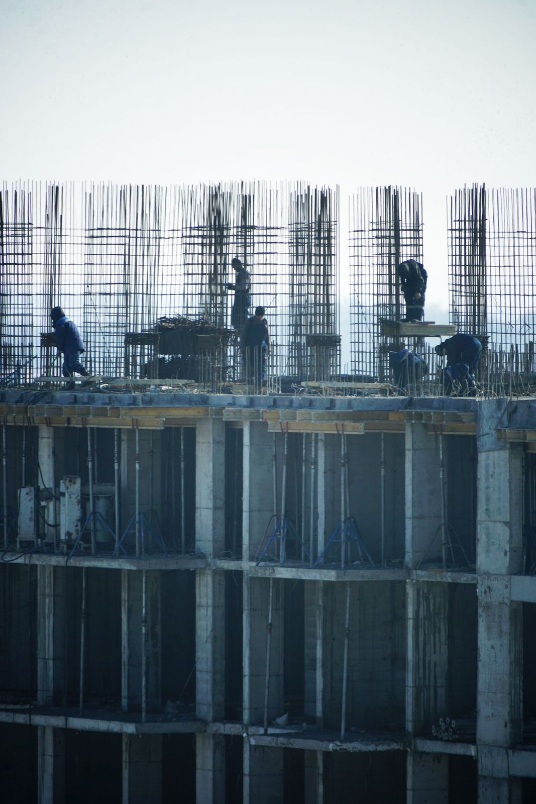 Construction workers at a high-rise building site with visible steel reinforcements